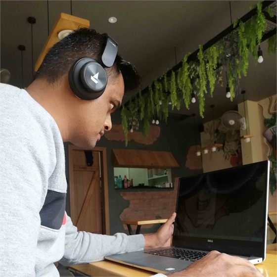 Sumeet working on his laptop at a café, wearing headphones