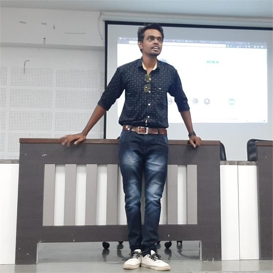 Sumeet speaking at a seminar with a presentation screen behind him