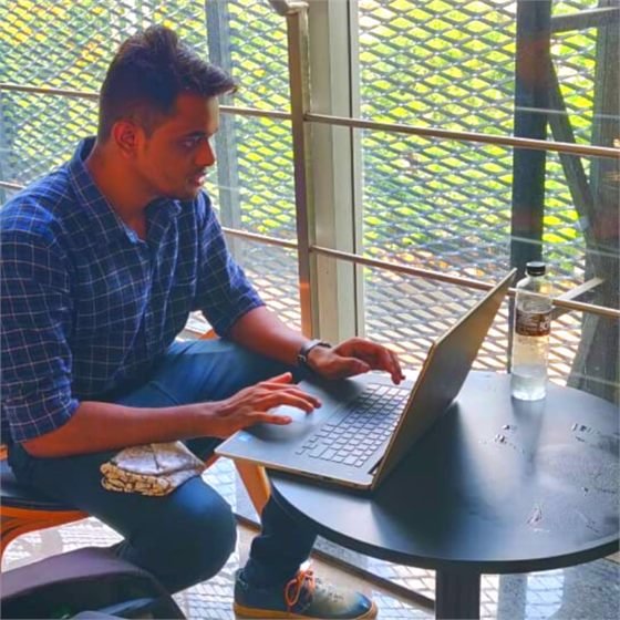 Sumeet working on his laptop outdoors on a balcony